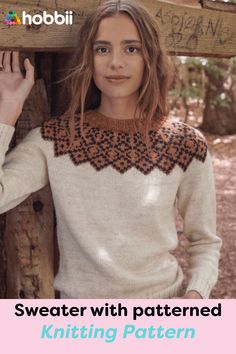 a woman standing next to a wooden structure wearing a sweater with geometric designs on it