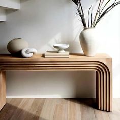 two white vases sitting on top of a wooden table next to a book shelf