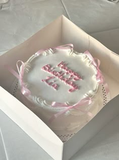 a birthday cake in a white box with pink ribbon around the edges that says happy bday