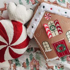 two knitted gingerbread houses and a teddy bear on a bed with christmas decorations