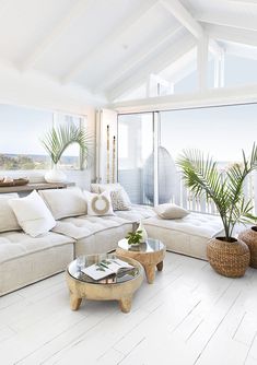 a living room with white furniture and large windows overlooking the ocean on a sunny day