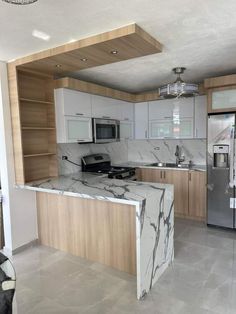 an empty kitchen with marble counter tops and stainless steel appliances in the middle of it