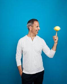 a man holding a yellow frisbee in one hand and smiling at the other