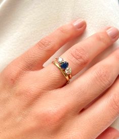 a woman's hand wearing a gold ring with blue and white stones on it