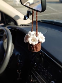 a car dashboard with a steering wheel hanging from it's center console, and a crocheted flower in the center