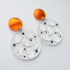 the earrings are decorated with white acrylic and black star accents, which include ghost silhouettes