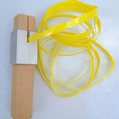 a piece of wood and some yellow string on a white surface with a wooden handle