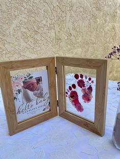 two wooden frames sitting on top of a table next to a vase filled with flowers