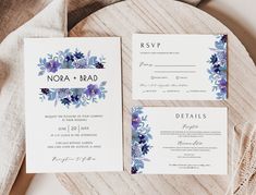 the wedding stationery is laid out on top of a wooden table with purple and blue flowers