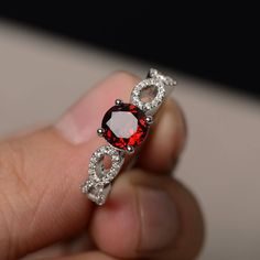 a hand holding a ring with red and white stones