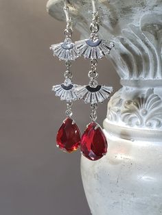 Dazzling diamond and ruby Deco jewelry inspired these long flapper style drop earrings.  Vibrant red teardrop shaped  rhinestone pendants dangle from fan shaped rhinestone connectors.  These earrings are extremely lightweight and comfortable to wear. The earrings measure 2  1/2 inches long and hang from silver plated lever back ear wires. These sparkling dangles are reminiscent of the sleek geometric jewelry worn by flappers during the Roaring Twenties. Perfect for a Great Gatsby themed wedding Antique Red Earrings For Formal Occasions, Red Art Deco Jewelry For Wedding, Red Pierced Dangle Chandelier Earrings, Vintage Red Dangle Chandelier Earrings, Art Deco Red Rectangular Jewelry, Gold Art Deco Earrings, 1920s Jewelry, Queen Earrings, Pearl Jewels