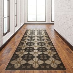 a black and white area rug in an empty room with wood flooring, large windows and brick wall