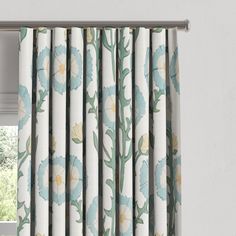 an open window with blue and white flowers on the curtain valance, in front of a window sill