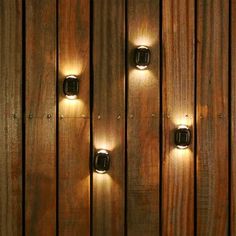 three lights are on the side of a wooden wall