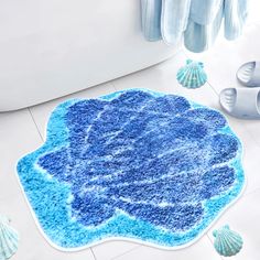 a blue rug is on the floor in front of a bathtub and seashells