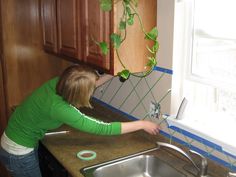 a woman washing plants in a kitchen sink