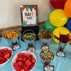 a table topped with lots of different types of candies and fruit in buckets