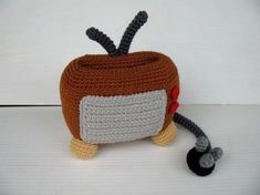 a small crocheted tv sitting on top of a white table next to a black object