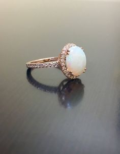 DeKara Designs Collection Our latest design! An elegant and lustrous Opal cabochon surrounded by beautiful diamonds in a halo setting. Metal- 18K Rose Gold, .750. This Specific Ring Is a Size 6 3/4 Stones- Center Features an Oval Fiery Australian Opal Cabochon Cut 2.20 Carats, 11.10 MM Long, 9 MM Wide, 44 Round Diamonds, H-I Color VS2-SI1 Clarity, 0.40 Carats. Latest of my creations. A beautiful Opal Halo Diamond Ring. The Opal is professionally prong set in between 4 double prongs. There are 10 Luxury Rose Gold Round Wedding Ring, Exquisite Rose Gold Round Cut Ring, Rose Gold Halo Setting Wedding Ring With Round Band, Elegant White Diamond Ring For Proposal, Luxury Rose Gold Opal Gemstone Ring, Elegant White Rings For Proposal, Luxury Opal Ring With Diamond Prong Setting, Rose Gold Halo Setting Round Wedding Ring, Rose Gold Halo Ring With Diamond Accents