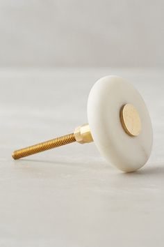 a close up of a white object with a gold screw in the middle on a table