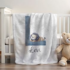 a teddy bear sitting next to a baby's crib with a lion blanket on it