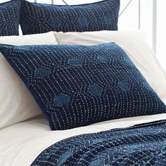 a bed with blue and white pillows on top of it