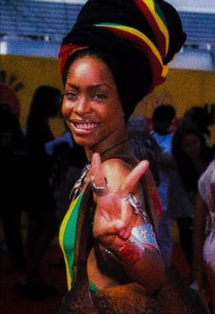 a woman wearing a colorful hat making the peace sign