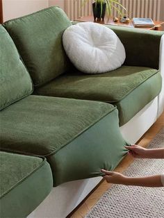 a woman pointing at a green couch with a white pillow on it's back