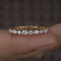 a person's hand holding a gold and white ring with five diamonds on it