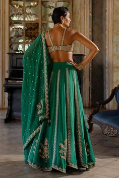 Emerald green lehenga with floral motifs hand embroidery. Comes with an organza base dupatta and gold dori and mirror embellished padded blouse. 
Components: 3
Pattern: Embroidered
Type Of Work: Dori, Mirror
Neckline: Round
Sleeve Type: Sleeveless
Fabric: Organza
Color: Emerald Green
Other Details: 
Lehenga:
Attached lining
Closure: Side zip
Blouse:
Padded
Attached lining
Closure: Back hooks
Dupatta:
Embroidered borders
Tassel edged
Karigari time: 186 hrs
Occasion: Mehendi and Haldi,Wedding - Az Mirror Lehenga, Paulmi And Harsh, Raw Silk Dress, Organza Lehenga, 1950’s Fashion, Green Mirror, Green Lehenga, Dress And Jacket Set, Embroidered Lehenga