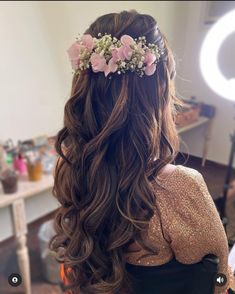 the back of a woman's head with long hair and flowers in her hair