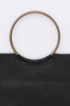 The Mini O Ring bag was inspired by our love of clean, minimalist design. The square and circle (and triangle are) the most reduced and basic geometric forms of any design language. The metal handles are sewn into the leather of the body so as to give the effect of the circle interrupting the square. This bag is just big enough to fit a phone, keys, and lip balm. This artisanal product is made of genuine leather. All scars are characteristics of the skin and not imperfections. We hope you enjoy Minimalist Bag With Round Handle For Everyday Use, Minimalist Everyday Bags With Magnetic Closure, Chic Geometric Shoulder Bag For Everyday, Modern Bags With Magnetic Closure And Round Handle, Modern Bag With Magnetic Closure And Round Handle, Minimalist Shoulder Bag With Detachable Handle, Modern Evening Bag With Hardware Details, Modern Evening Bag With Hardware, Modern Evening Bags With Hardware