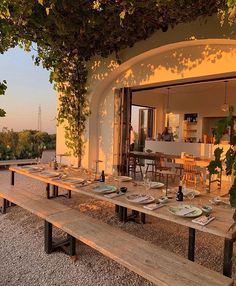 an outdoor dining area with wooden benches and tables set up for dinner on the patio