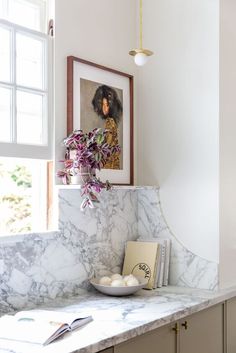 a marble counter top in a kitchen with a potted plant on it and pictures above