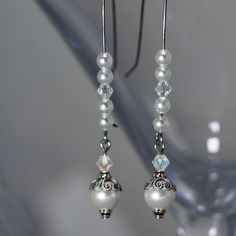 These White Pearl and Crystal beaded earrings are accented with silver filigree bead caps. The earrings are just under 3 inches long. Formal White Pearl Crystal Earrings, Elegant Pierced Linear Earrings For Weddings, Elegant White Crystal Earrings For Gift, Elegant White Crystal Earrings For Anniversary, Elegant White Round Crystal Earrings, Adjustable Crystal Earrings For Wedding, Sterling Silver Pierced Pearl Earrings For Wedding, White Pearl Crystal Earrings For Pierced Ears, Adjustable White Crystal Earrings