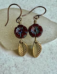 "small flower and leaf earrings   dark red czech glass earrings   boho dangle earrings These small (9mm) Czech glass flowers are dark red/burgundy with a blue Picasso coating. Dangling below each one is a small, antiqued brass leaf charm. Small hook ear wires are antiqued brass. Length of earrings from top of ear wires is 1 1/2\". Glass flowers measure 9mm. Leaves measure 12mm long. You can enter my shop here: gypsydangles.etsy.com" Bohemian Burgundy Jewelry Gift, Bohemian Burgundy Jewelry As Gift, Bohemian Czech Glass Dangle Flower Earrings, Nickel-free Czech Glass Flower Earrings, Handmade Burgundy Earrings For Gift, Burgundy Dangle Earrings, Red Bohemian Dangle Flower Earrings, Red Bohemian Drop Flower Earrings, Czech Glass Flower Earrings With Flower Charm