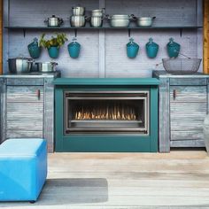 an outdoor fireplace with pots and pans on the shelves above it, next to a blue ottoman