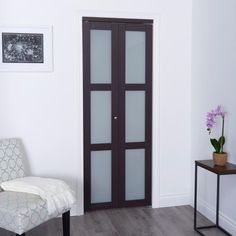 a living room with a white chair and black glass doors in front of the door