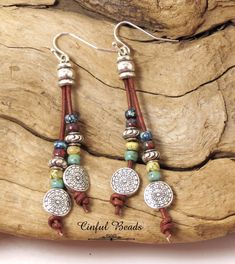 the earrings are made with beads and leather cord, which is attached to a piece of wood