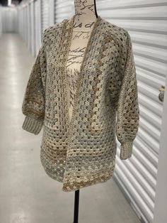 a mannequin wearing a crocheted sweater in front of a storage unit