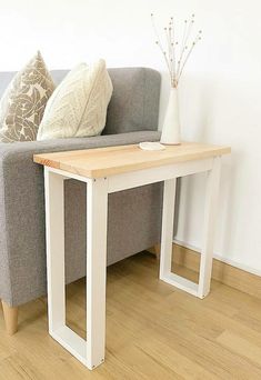 a couch with a table on it in front of a white wall and wooden floor