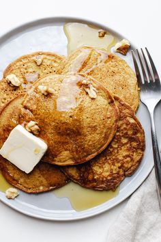 pancakes with butter and maple syrup are on a plate next to a knife and fork