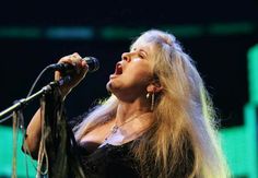 a woman with long blonde hair singing into a microphone