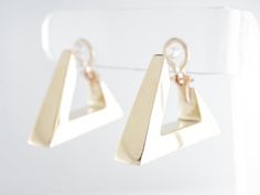 These fancy modern dangle earrings are finished in 14 karat yellow gold. They are secured by an omega closure and face forward for a good view of the triangle design from the side view. The triangles have lovely open spaces at the closure, existing as a design element as well as a functional space for wearing them.Composition: 14 Karat Yellow GoldGeneral Characteristics:Measurements: 1.5 inches x 8.19 mmTotal Gram Weight: 19.6Era: Modern 1970-PresentInscription: 14 KT--ALL PIECES ARE SUBJECT TO Good View, Gold Triangle, Face Forward, Functional Space, Art Deco Engagement, The Triangle, Triangle Design, Antique Engagement, Deco Engagement Ring