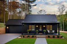 a house with a black metal roof and two chairs on the front porch, surrounded by green grass