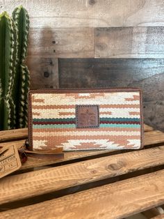 a small purse sitting on top of a wooden table next to a cactus and cacti