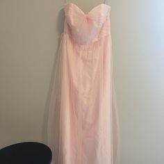 a pink dress hanging up against a wall