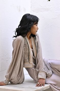 The Meraki jacket is the perfect addition to your wardrobe for a light weight layer than can be dressed up or down easily. Featuring exquisite hand embellished details and lined edging this light weight raw silk body blouses beautifully and allows for comfortable movement.  Size | One Size  AUS 8 - 12 UK  8 - 13 US 4 - 8 EU 36 - 40 Fit |  *cropped at mid waist *Relaxed fit *Balloon sleeves - generous blouse  Fabric | Features  *Hand loomed + hand dyed raw silk  *beaded fringing details  Paired w Fall Sets With Set-in Long Sleeves, Chic Long Sleeve Silk Sets, Chic Silk Long Sleeve Sets, Evening Long Sleeve Shrug For Fall, Elegant Long Sleeve Sets With Draped Sleeves, Elegant Sets With Draped Long Sleeves, Elegant Long Sleeve Fall Shrug, Embellished Long Sleeve Silk Outerwear, Fitted Outerwear With Blouson Long Sleeves