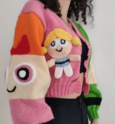 a woman with curly hair wearing a pink knitted sweater and holding a stuffed toy