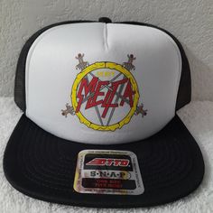 a white and black mesh hat with the word metal on it, next to a sticker